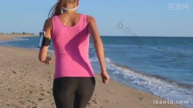 健身妇女慢跑在海滩上听音乐耳机从智能手机mp播放器后视图